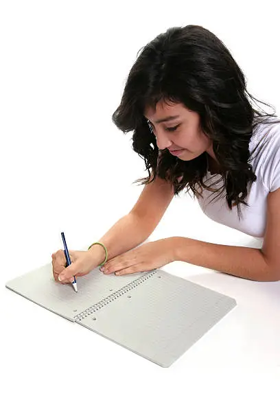 A teenage girl writing in a spiral notebook