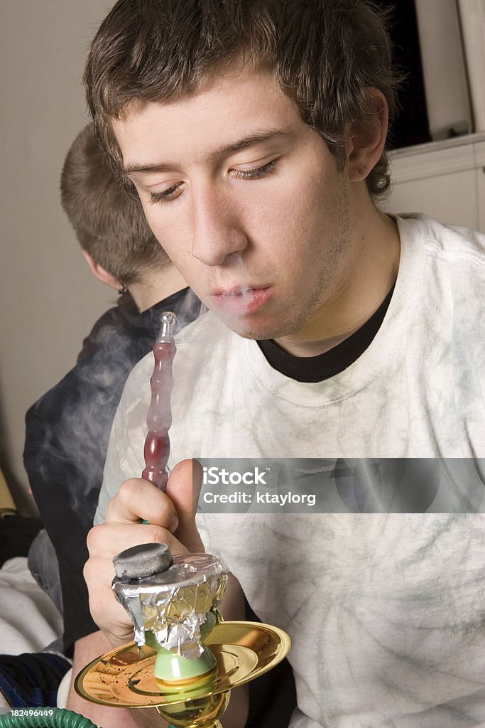 Teen smoking from hookah pipe Smoke comes out of teen's nose as he smokes a hookah Hookah Stock Photo