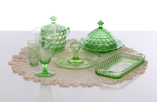 A still life setup of various types and patterns of old American Depression Glass on a hand crocheted doily.
