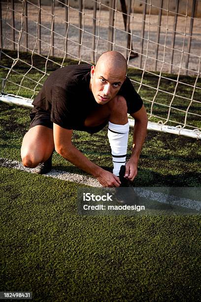 Foto de Jogador De Futebol No Ramo Seu Calçado No Gol e mais fotos de stock de Adulto - Adulto, Ajoelhar, Ajustar