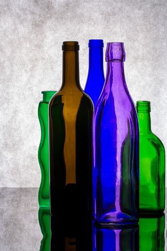 Still life with colored glass bottles on a gray background