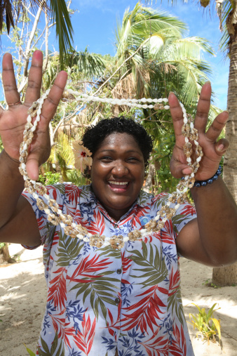 A smiling happy Fijian woman welcomes you to Fijiwith a necklace of seashells