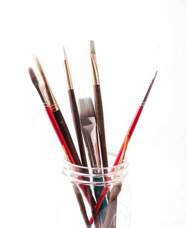 A collection of artists paint brushes in a jar
