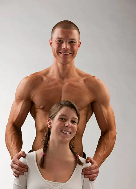 Photo of smiling muscular build man holding cute young woman XXXL