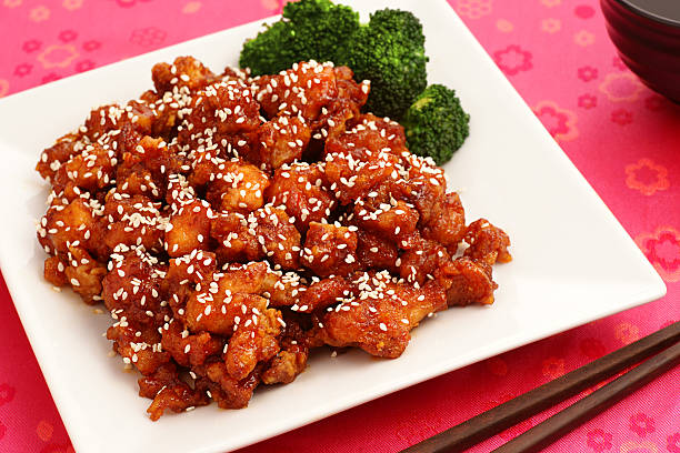 Sesame chicken with broccoli on square plate on red table stock photo