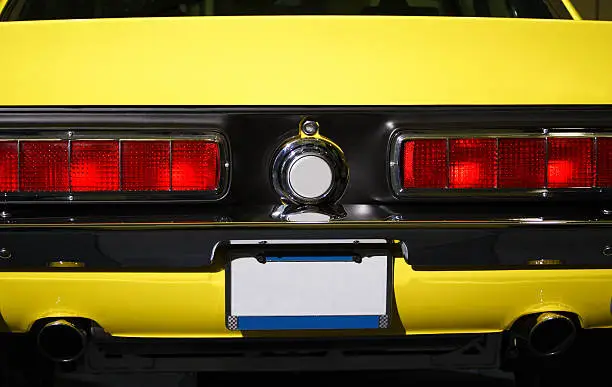 Photo of Rear view of classic Ford Mustang muscle car in yellow