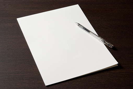 Close-up shot of blank document with pen on wooden desk.