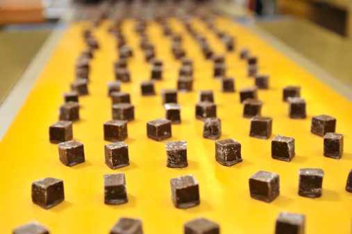 Caramels going into a coating machine in a candy factory.