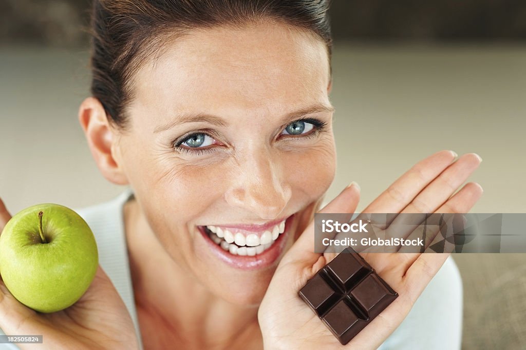 Uśmiechnięta kobieta Trzymając kawałek czekolady i apple - Zbiór zdjęć royalty-free (Kobiety)