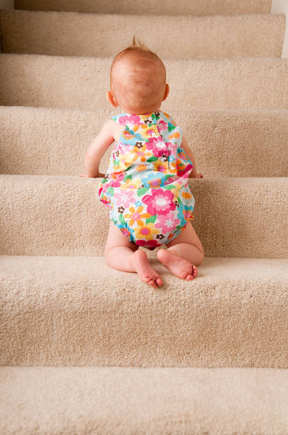Baby Girl Crawling Up Carpeted Steps Alone stock photo