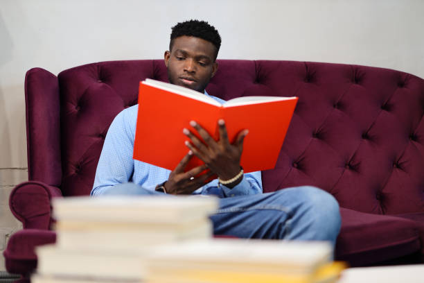 istock A young man engrossed in reading and studying, surrounded by books in a comfortable setting. 1825067358