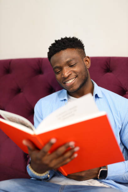 istock A young man immersed in a book, radiating happiness and confidence in a cozy library setting. 1825067364