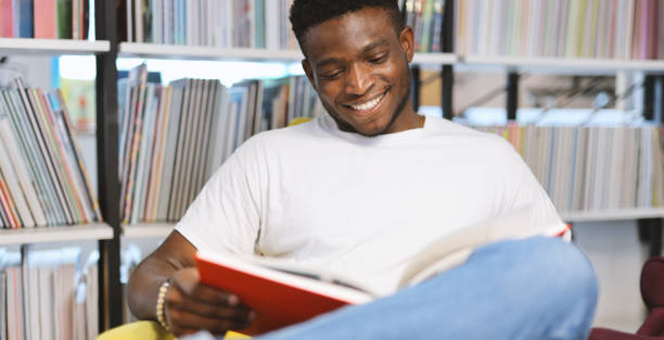 istock Happy young student in a library, studying with a book, exuding cheerful joy in education. 1825067912