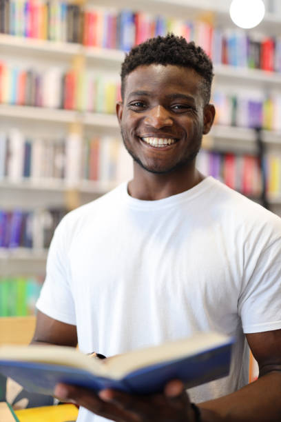 istock Joyful young student in a university library, confidently choosing books, exuding happiness and confidence. 1825067921