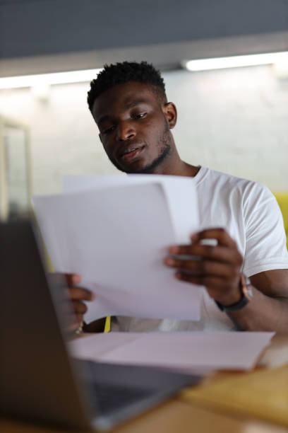 istock Serious African American businessman reading documents in a modern office, exuding professionalism and dedication. 1825068512