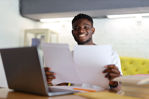 Happy businessman in an office, reading a document, exuding joy and success in professional achievements.