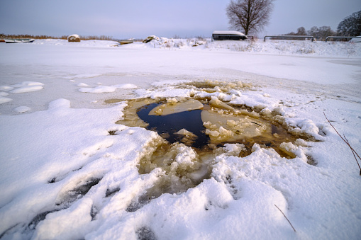 Hole in the thin ice. Someone fell through the ice. Dangerous concept. Freezing and melting time for ice on the water reservoirs in winter