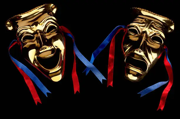 Dramatically lit antique brass comedy and tragedy theater masks with blue and red ribbons isolated on a black background. Please see my portfolio for more variations of these masks.