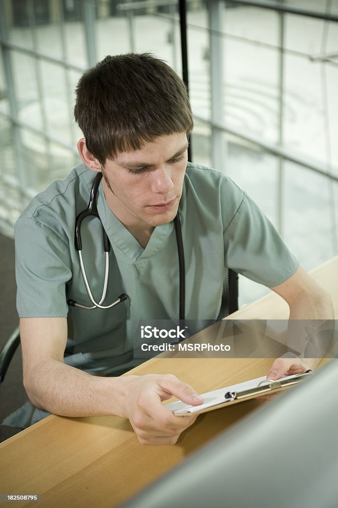 Medical Portrait "Portrait of a male nurse sitting down, reviewing some paperwork." 20-24 Years Stock Photo
