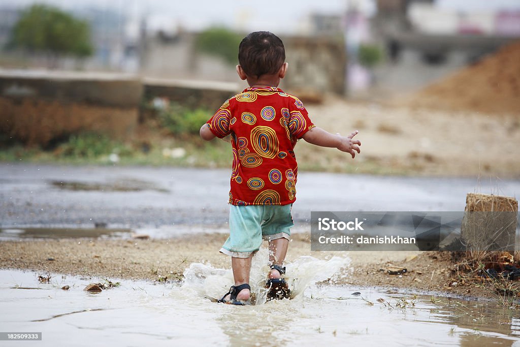 Giovane ragazzo suona la libertà dell'acqua piovana Pozzanghera Schizzare - Foto stock royalty-free di 2-3 anni