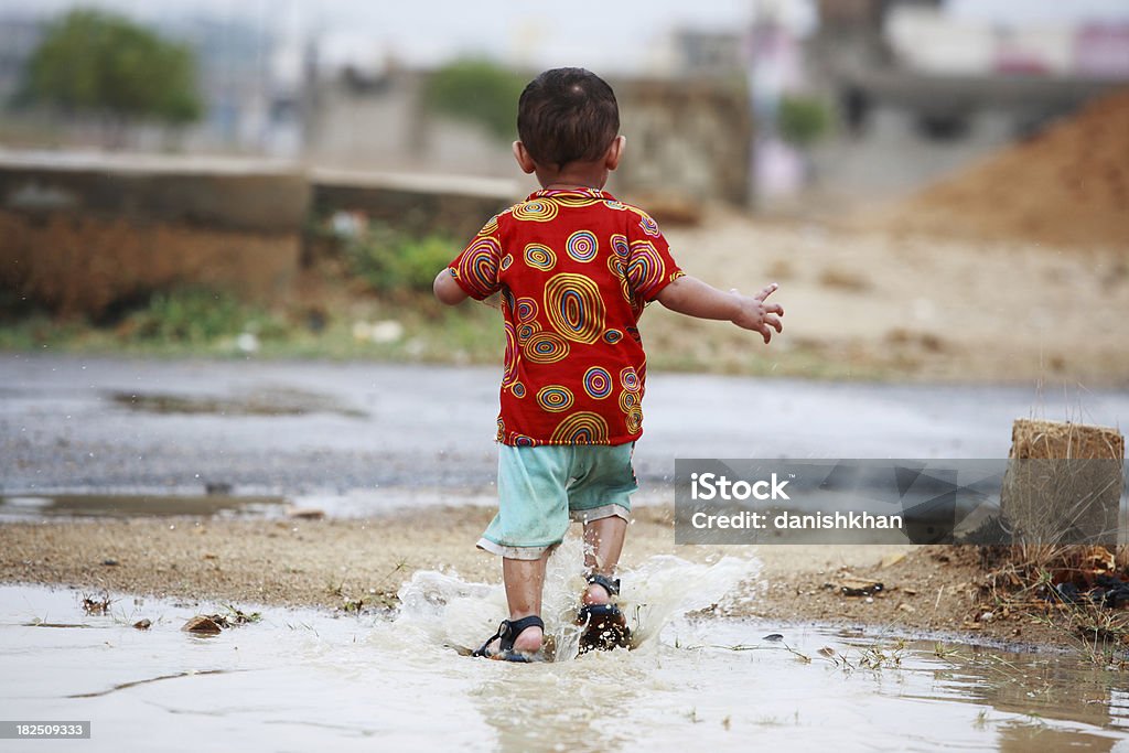 Młody chłopiec bawi się wolnością deszczową Kałuża Chlapać - Zbiór zdjęć royalty-free (2-3 lata)