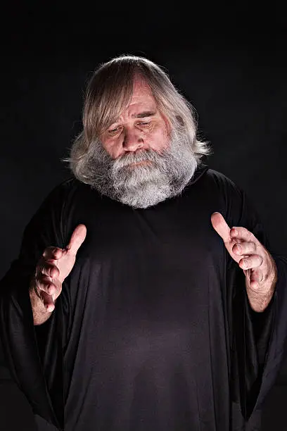 "A mature man in a meditative stance, on a black background."