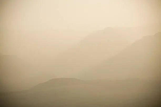 "The air filled with dust and haze, you can only see the subtle hints of the mountains and desert valley below in Death Valley, California."