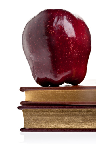 An apple on gold edged books.