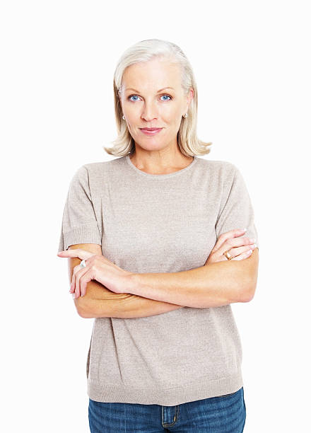 Smiling confident mature woman standing arms crossed against white Portrait of a happy elderly woman standing arms crossed against white women beautiful studio shot isolated on white stock pictures, royalty-free photos & images