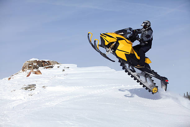 Snowmobile jumping as he tops the mountion.