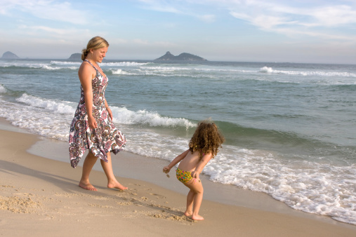 Young mother having quality time with her little daughter on the beach. Rio de Janeiro, Brazil.