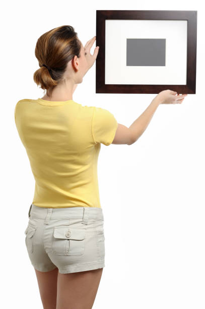 istock Young Woman Hanging Frame on White 182511711