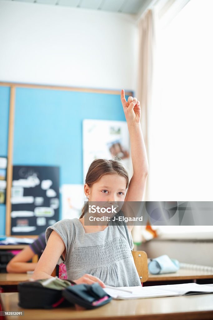 Confident school girl raising hand to answer a question Pretty smart school girl with hand raised , volunteering to answer a question 8-9 Years Stock Photo