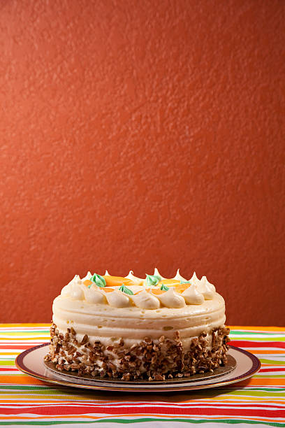 Carrot cake with icing and pecans.Plenty of room for copy on red background wall.  Colorful strip tablecloth.