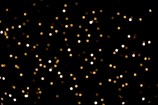 Festive abstract template with bokeh lights, photographic effect. Golden defocused Christmas light spots on black background. Beautiful Blurred Holiday Texture for design