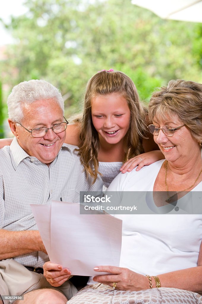 Idosos e filha olhando no documento - Foto de stock de Abraçar royalty-free