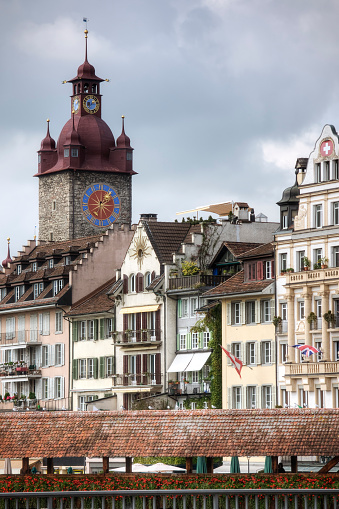 Photo of Lucerne Switzerland showing the Rathaus (city hall) and roof of the famous Kapelbrücke covered bridge located in the historic center of town.