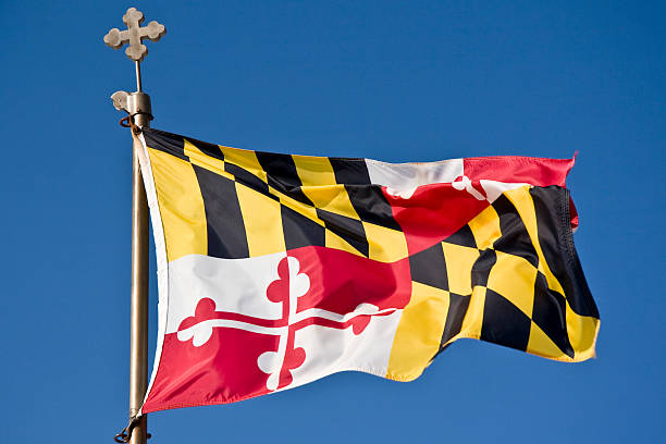 The Maryland state flag waving briskly in the wind.  The design of the flag is taken from the coat of arms of the Calvert family. The symbol in the red and white sections represents a greek cross.  Notice a similar symbol on the top of the flagpole.F