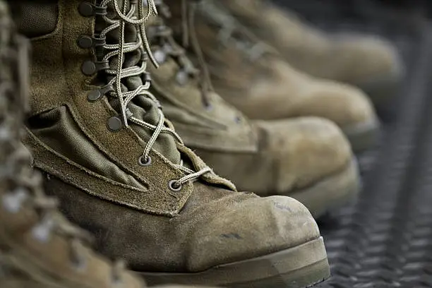 A row of worn down combat boots with a shallow DoF.