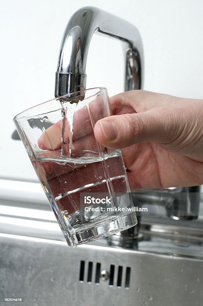 Pouring a glass of water from a faucet Filling a glass with fresh water from a faucet. Hand holding the glass Drinking Glass Stock Photo