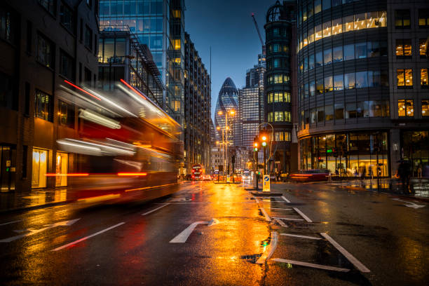 Financial district of London Traffic at the financial district of London on a rainy autumn day. Moody light at dusk. Reflections of streets lights and building on the wet street. london gherkin at night stock pictures, royalty-free photos & images