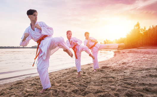 Children karate section training on beach sand near the river