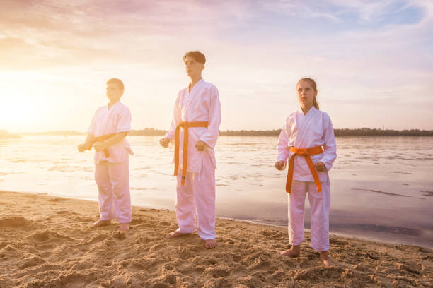 Children karate section training on beach sand near the river