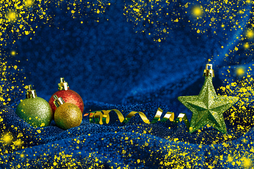 Christmas ornaments on a blue sparkling textile background. Space for copy.