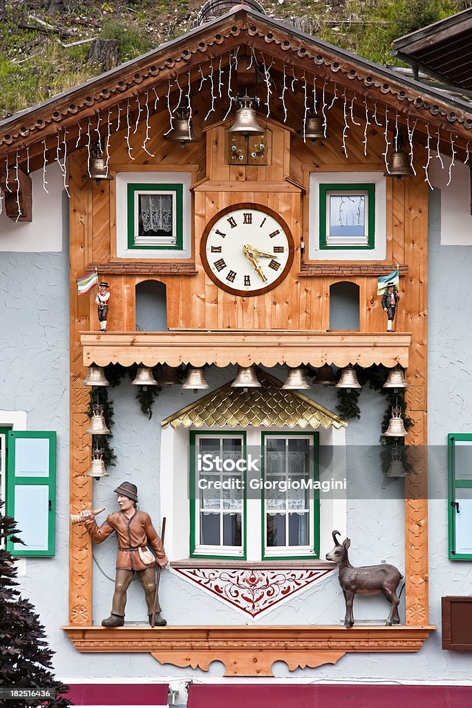 Alpine Wooden Facade with Clock and Bells, Dolomites in Summer Original wooden facade in the alpine town of Canazei. The location is the Val di Fassa (Trentino-Alto Adige, Italy) during the summer season. Canazei Stock Photo