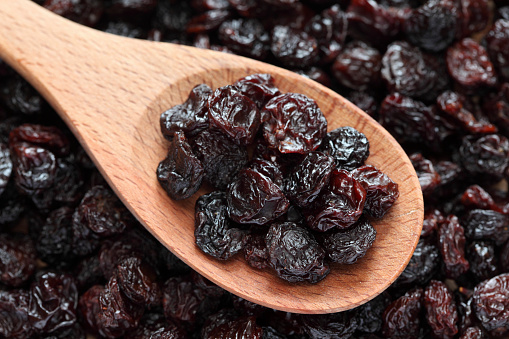 Raisins in a wooden spoon on raisins background. Close-up.Please see: