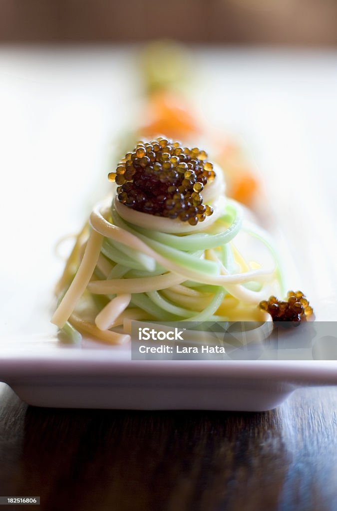 Noodles topped with caviar Pale green and straw colored noodles topped with a large dollop of osetra caviar Ambient Light Stock Photo