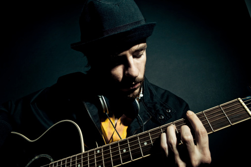 Portrait of a young adult male playing acoustic guitar