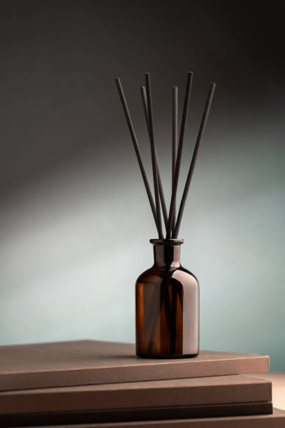 istock Aroma reed diffuser dark glass on green background with volumatic light 1825176200