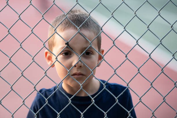 istock Sad little boy looking through a fence 1825179484